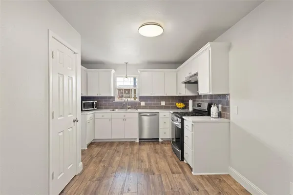 a kitchen with cabinets wooden floor and stainless steel appliances