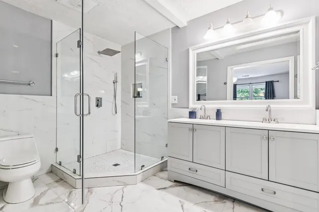 a bathroom with a shower sink mirror and toilet