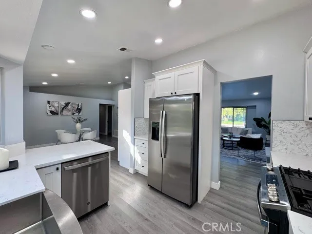 a kitchen with stainless steel appliances granite countertop a refrigerator a stove and a wooden floors