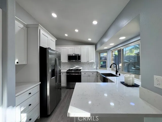 a large kitchen with stainless steel appliances a large counter top a stove a refrigerator a sink and a granite counter tops