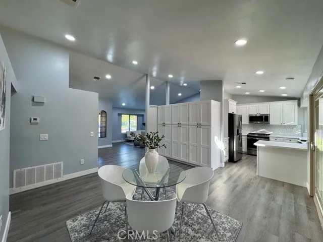 a living room with stainless steel appliances furniture a rug and a kitchen view