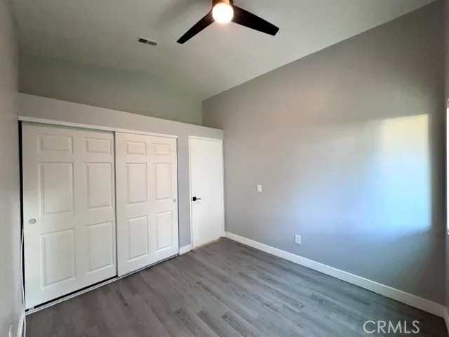 an empty room with a ceiling fan and wooden floor