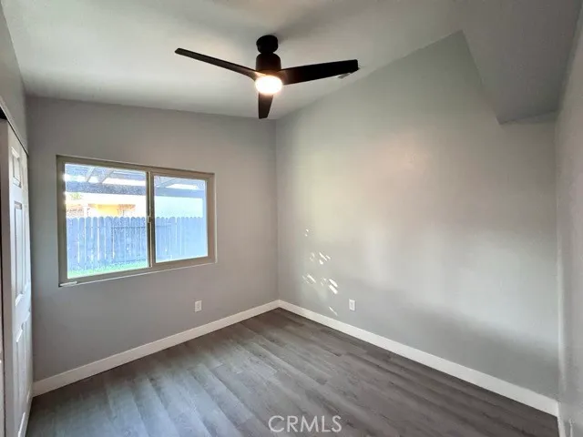an empty room with wooden floor fan and windows