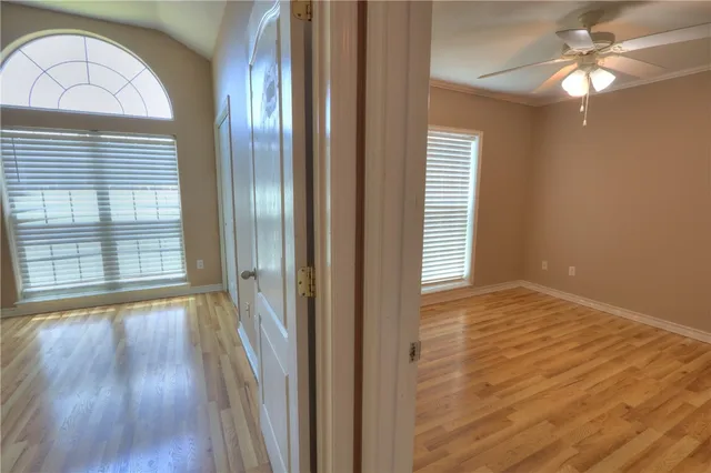 a view of empty room with wooden floor and fan
