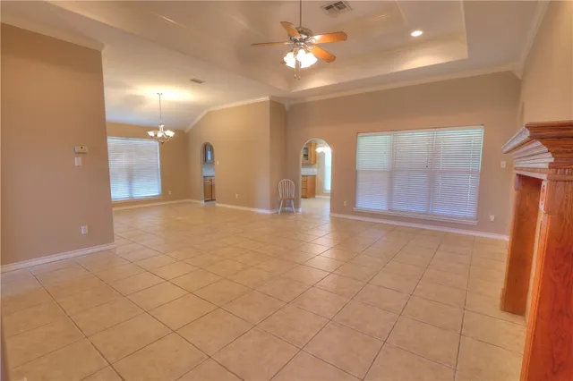 an empty room with a chandelier fan and glass door
