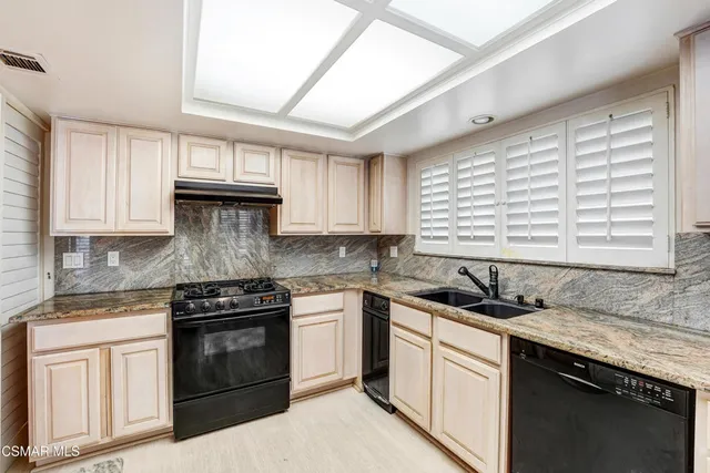 a large kitchen with stainless steel appliances granite countertop a stove a sink and a refrigerator