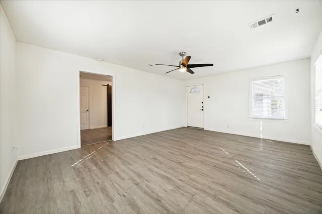 a view of empty room with wooden floor and fan