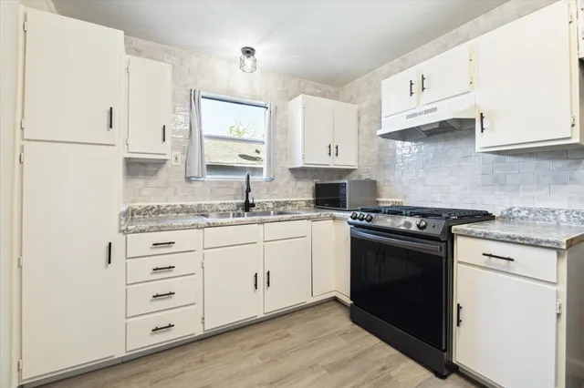 a kitchen with granite countertop white cabinets and white appliances