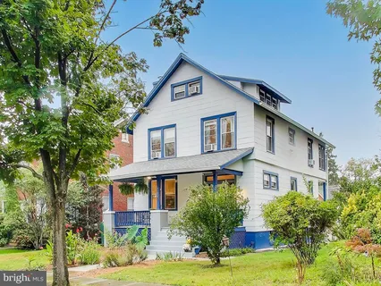 a front view of a house with garden and trees