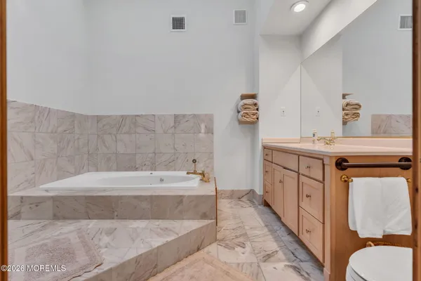 a bathroom with a tub sink toilet and mirror