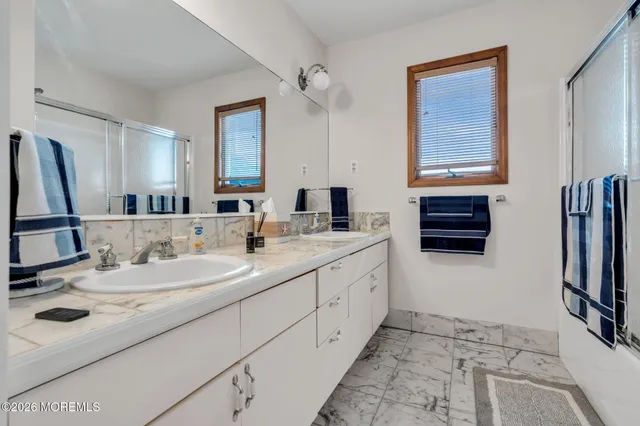 a bathroom with a double vanity sink a mirror and a bathtub