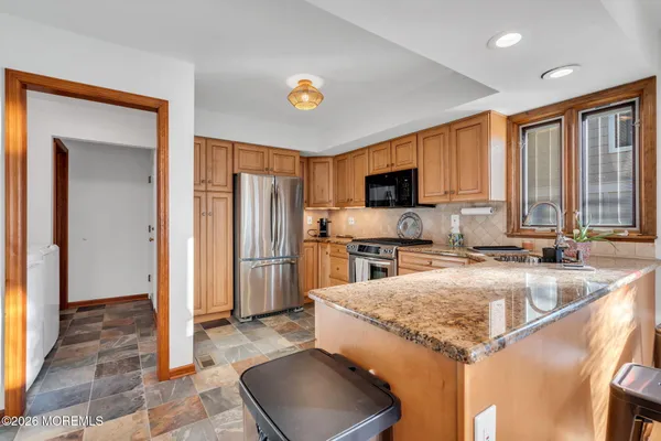 a kitchen with granite countertop a sink a counter top space cabinets and stainless steel appliances