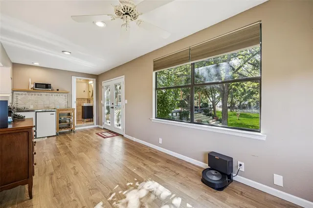 a view of an empty room with a window and kitchen view