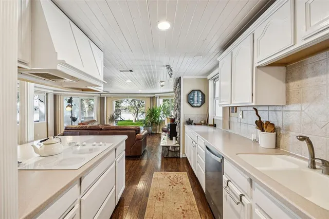 a large kitchen with kitchen island a large window a sink and stainless steel appliances