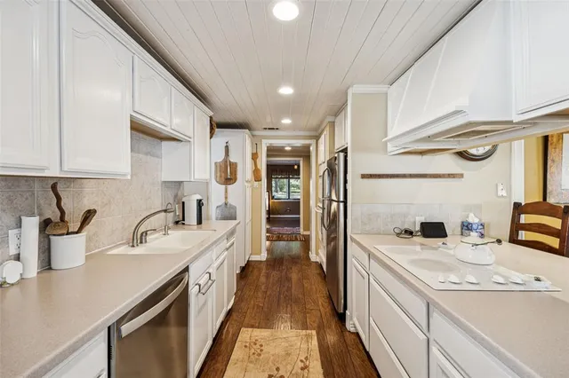 a kitchen with granite countertop a sink a counter space cabinets and stainless steel appliances