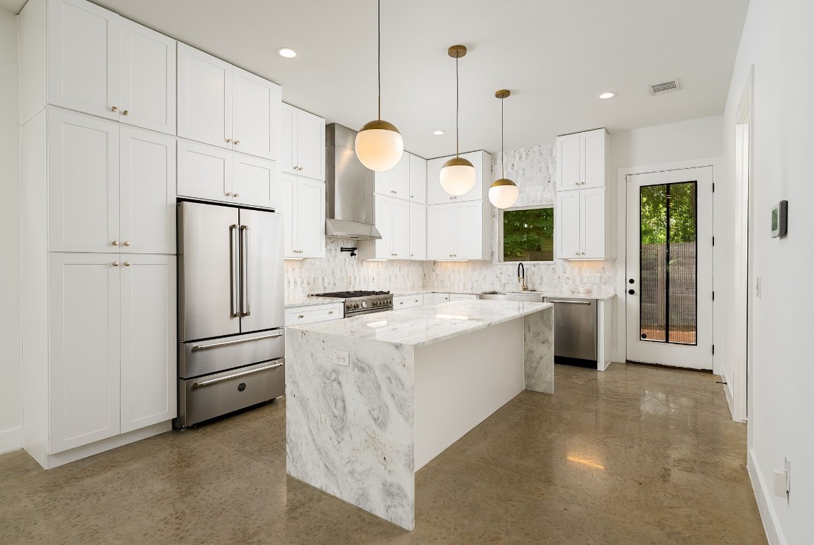 a large white kitchen with a refrigerator a sink and cabinets