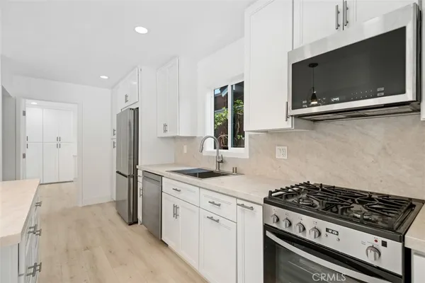 a kitchen with stainless steel appliances a stove a microwave a sink and cabinets