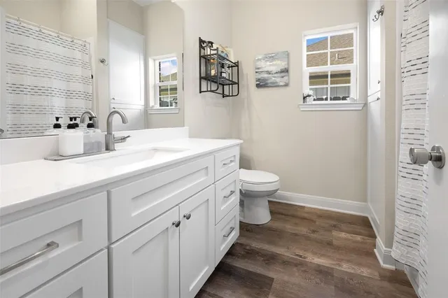 a bathroom with a granite countertop sink mirror vanity and toilet
