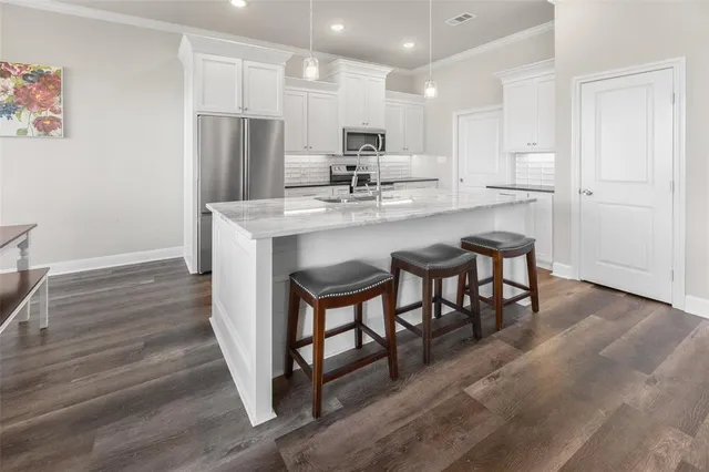 a kitchen with kitchen island white cabinets and stainless steel appliances