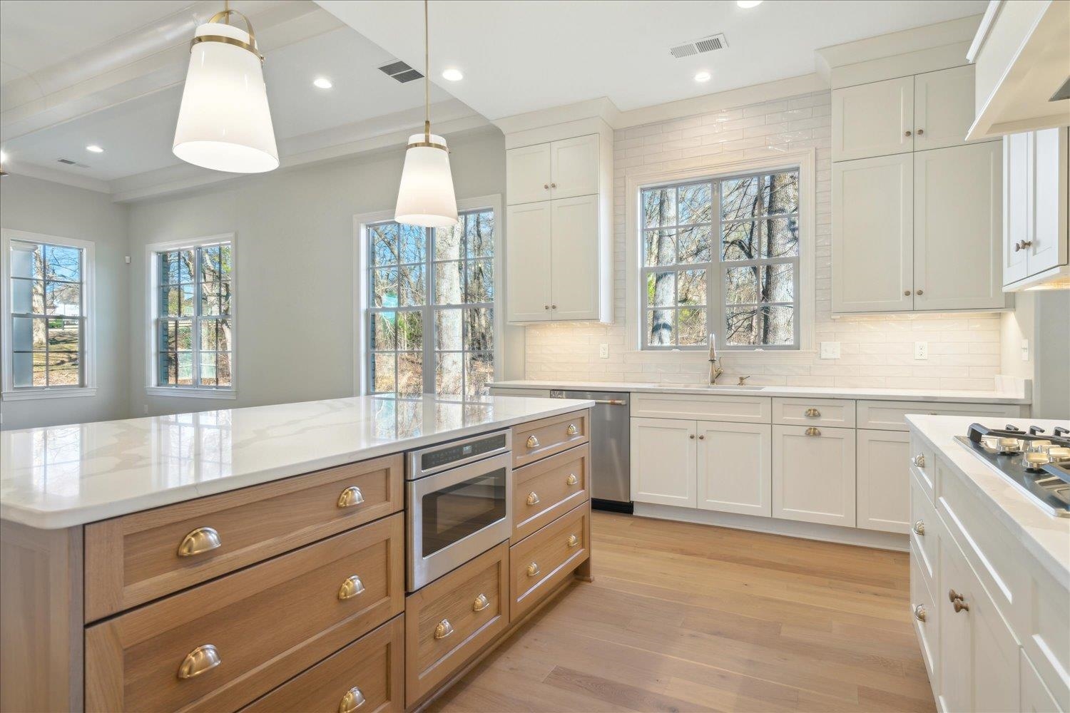 12620 Miss Cloud Road Collierville, TN 38017 - Photo 14 of 38 Kitchen with stainless steel appliances, decorative light fixtures, white cabinetry, a center island, and light stone counters