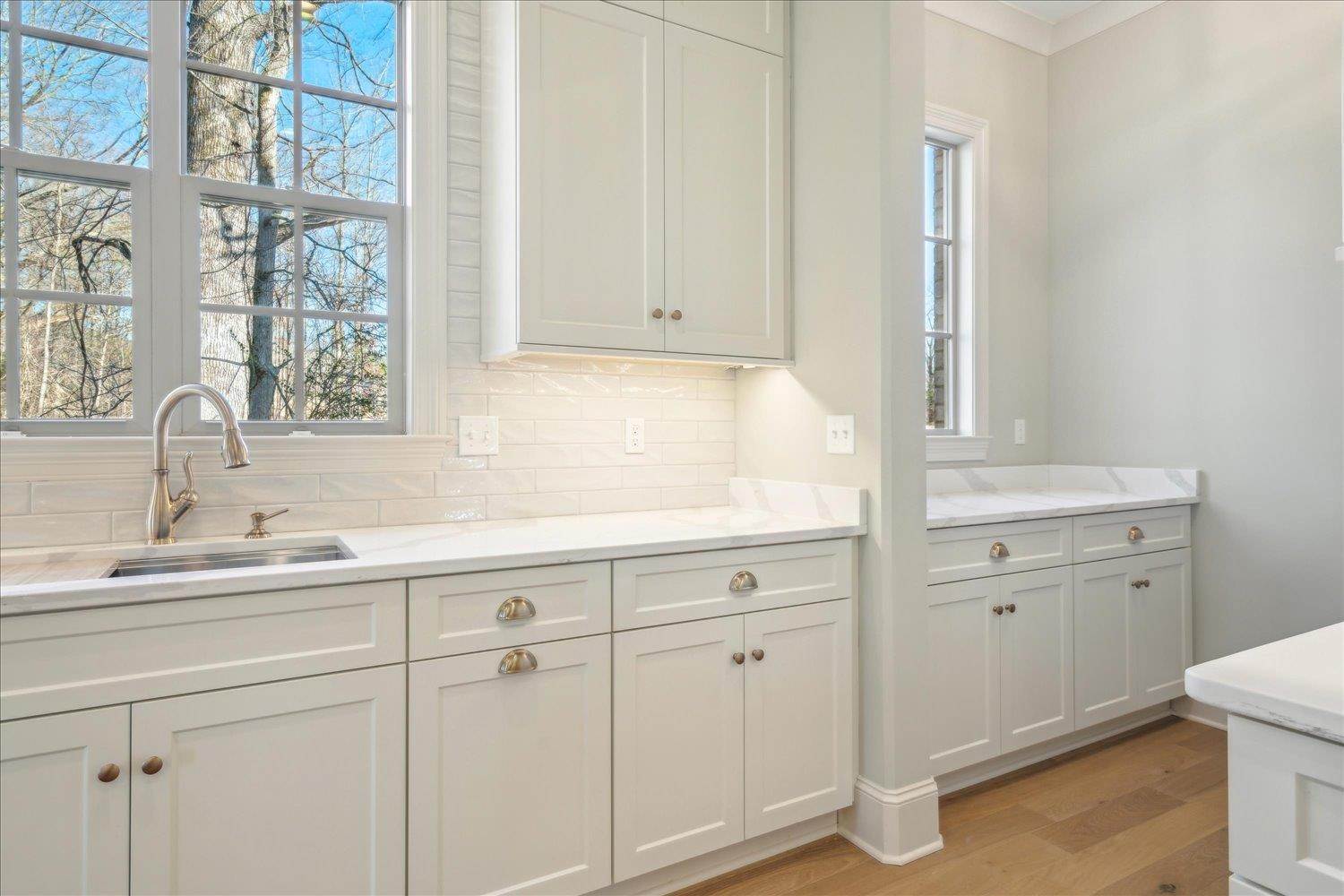 12620 Miss Cloud Road Collierville, TN 38017 - Photo 15 of 38 Kitchen with light stone counters, light hardwood / wood-style floors, tasteful backsplash, white cabinetry, and sink