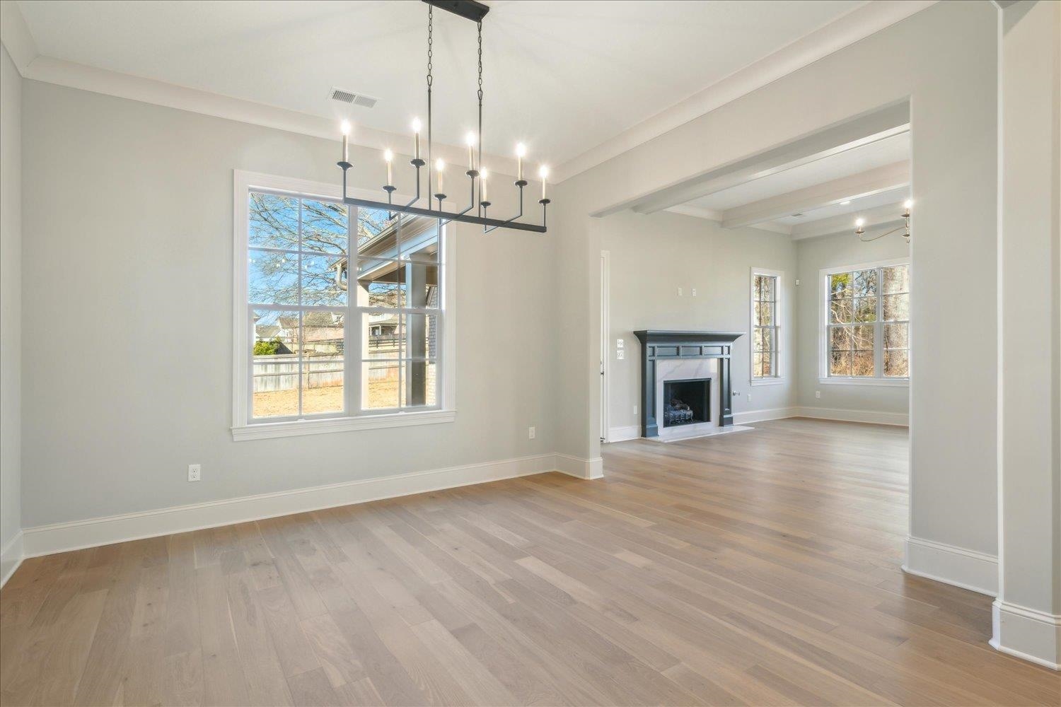 12620 Miss Cloud Road Collierville, TN 38017 - Photo 16 of 38 Unfurnished living room featuring crown molding, beam ceiling, a notable chandelier, and light hardwood / wood-style flooring