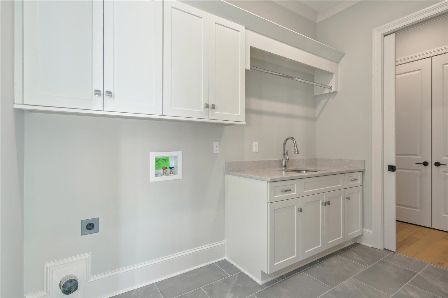 12620 Miss Cloud Road Collierville, TN 38017 - Photo 18 of 38 Laundry room featuring sink, electric dryer hookup, light tile patterned floors, and cabinets