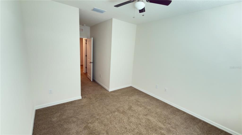 1881 Hovenweep Road Wesley Chapel, FL 33543 - Photo 17 of 18 an empty room with a ceiling fan and carpet