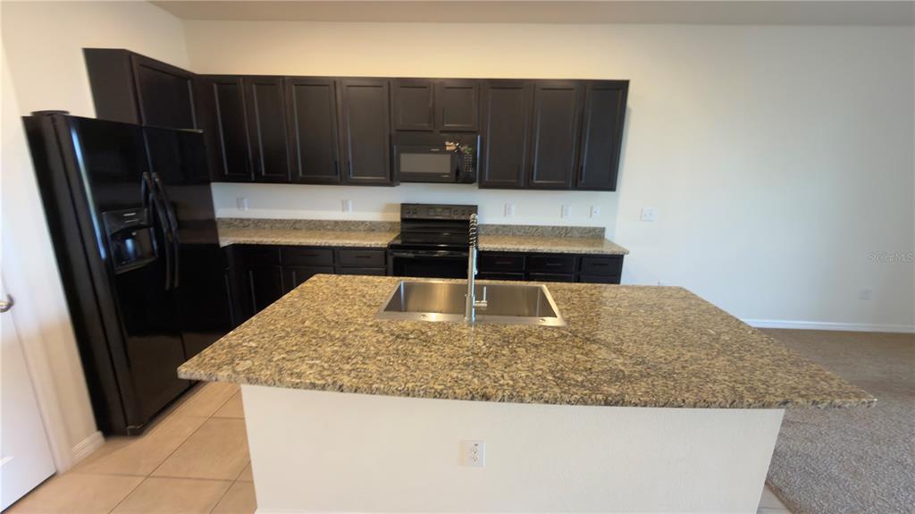 1881 Hovenweep Road Wesley Chapel, FL 33543 - Photo 4 of 18 a kitchen with granite countertop a refrigerator a stove and wooden cabinets