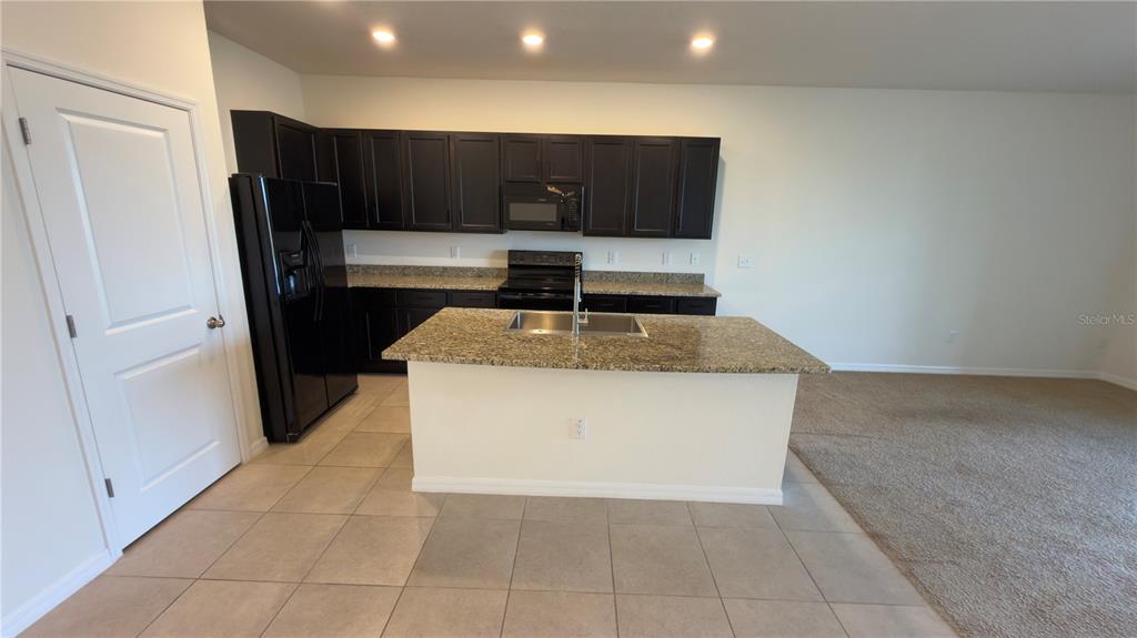 1881 Hovenweep Road Wesley Chapel, FL 33543 - Photo 5 of 18 a kitchen with kitchen island granite countertop wooden cabinets and refrigerator