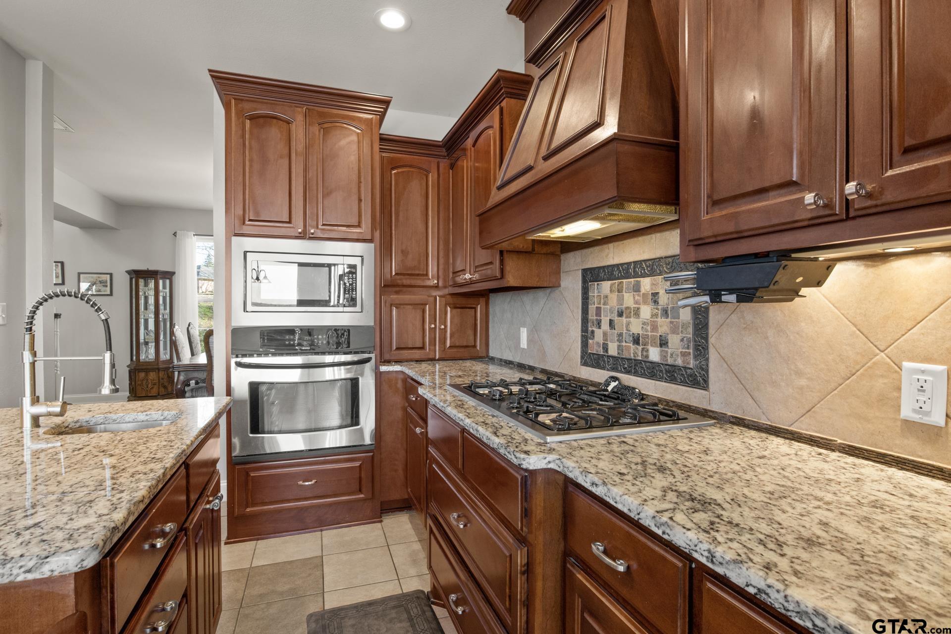 59 Private Road Pittsburg, TX 75686 - Photo 14 of 45 a kitchen with stainless steel appliances granite countertop a stove a sink dishwasher and refrigerator with wooden cabinets