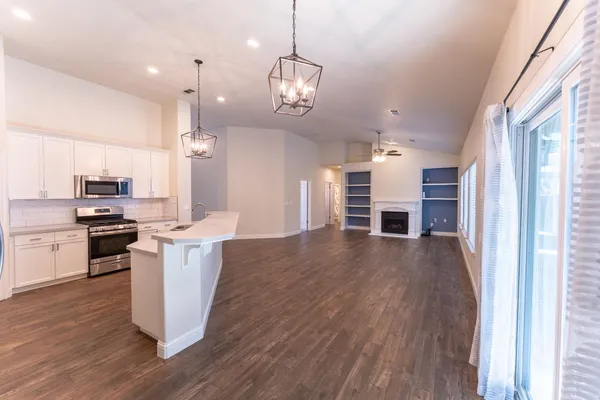 a kitchen with stainless steel appliances kitchen island granite countertop a stove a refrigerator a sink a oven and a wooden floor