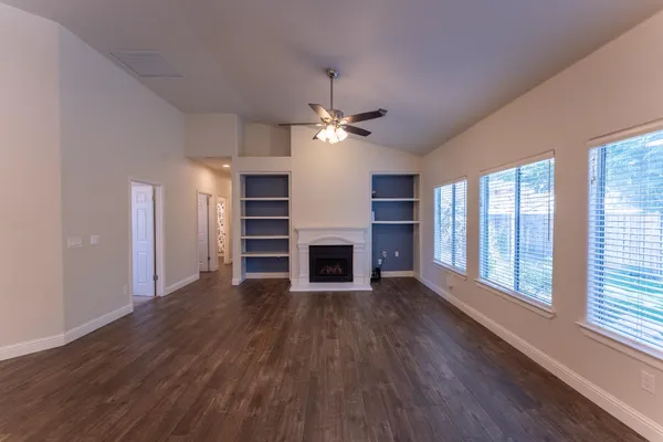 a view of a livingroom with a fireplace a ceiling fan and windows