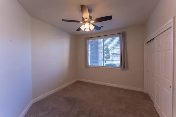 en empty room with window and chandelier fan