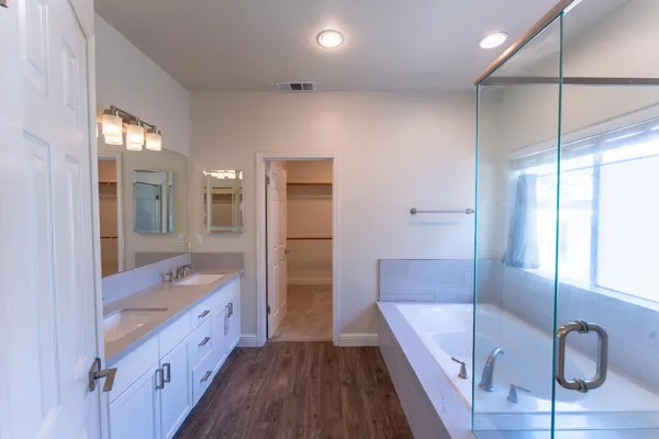 a bathroom with a tub a sink and a large mirror