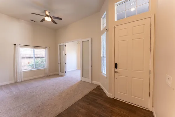 a view of empty room with wooden floor and fan