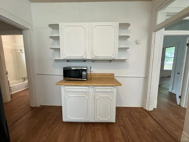 a kitchen with a hard wood floor white cabinets and white appliances