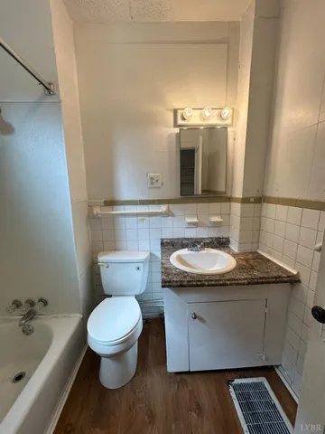 a bathroom with a granite countertop toilet sink and mirror