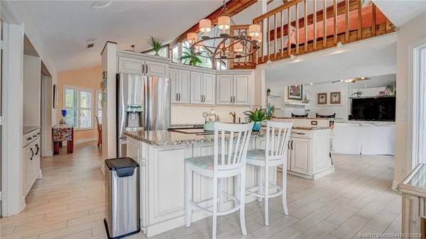 a kitchen with stainless steel appliances kitchen island granite countertop a table chairs and a view of living room