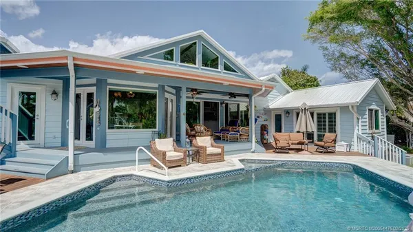 a view of a patio with couches table and chairs under an umbrella with a small yard