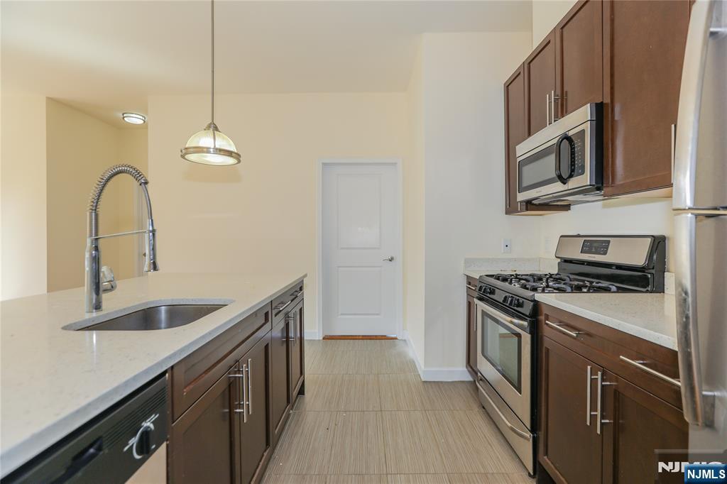 4 Main Street, Unit F Edgewater, NJ 07020 - Photo 9 of 20 a kitchen with stainless steel appliances granite countertop a sink a stove and a wooden floors