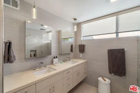 a bathroom with a double vanity sink toilet and a mirror