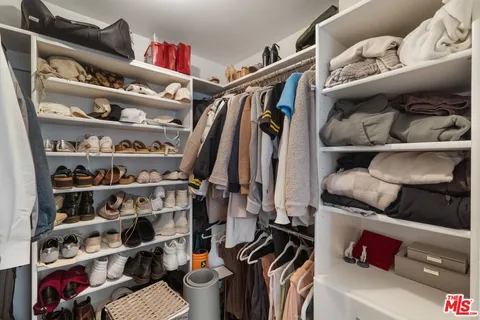 a view of walk in closet with clothes and shoes