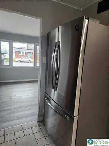 a view of a refrigerator in kitchen and an empty room