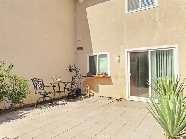 a view of a patio with table and chairs and potted plants with wooden fence