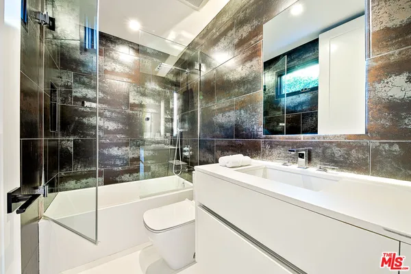 a bathroom with a sink and mirror with bathtub