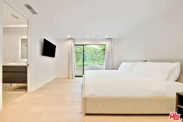 a large white bed in a room next to a window