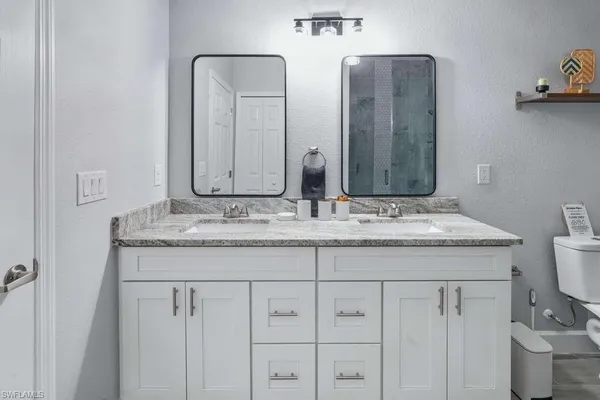 a bathroom with a granite countertop sink a toilet and a mirror
