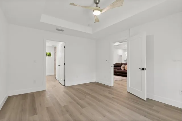 an empty room with wooden floor and ceiling fan