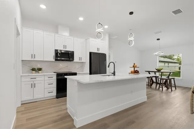 a large kitchen with cabinets chairs and wooden floor